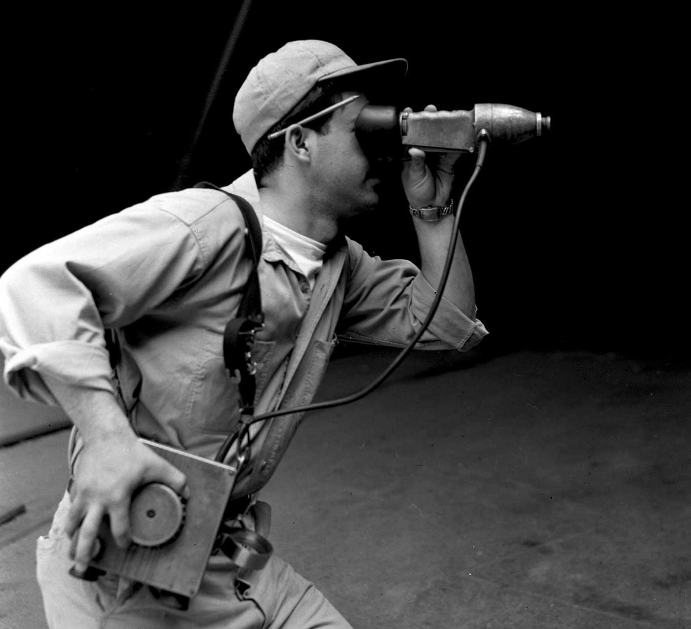 A worker using a spectroscope to observe steel color and gauge temperature.